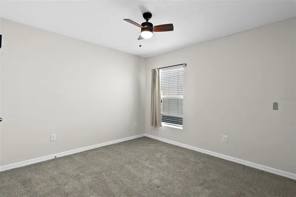 an empty room with ceiling fan and windows