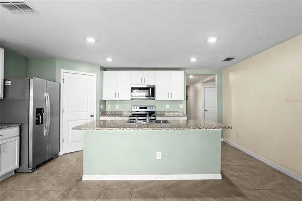 a kitchen with stainless steel appliances granite countertop a refrigerator a stove and a sink