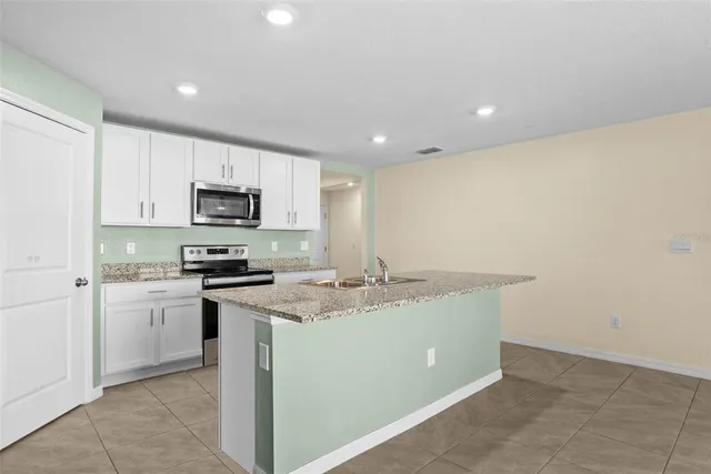 a kitchen with a sink a stove top oven and white cabinets