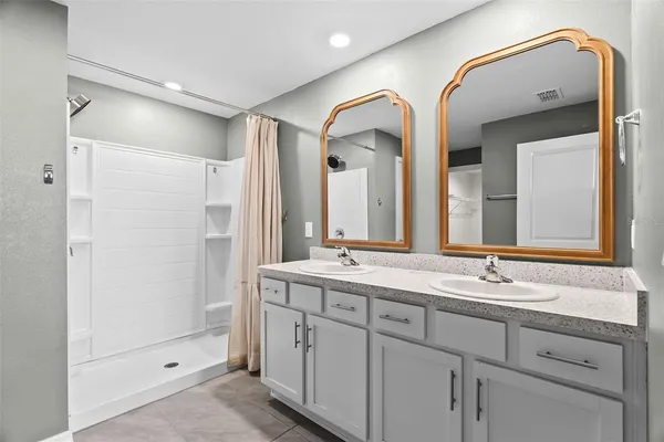 a bathroom with a double vanity sink and mirror with shower