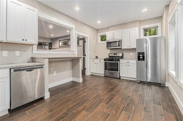 a kitchen with granite countertop a refrigerator and a stove top oven