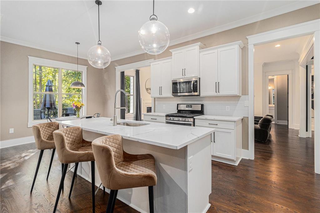 519 Holcomb Bridge Road Norcross, GA 30071 - Photo 10 of 31 a large kitchen with sink a microwave oven a stove and a dining table with wooden floor