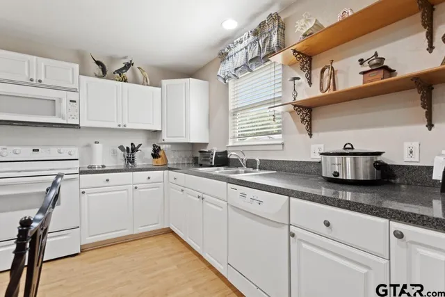 a kitchen with granite countertop white cabinets and white appliances
