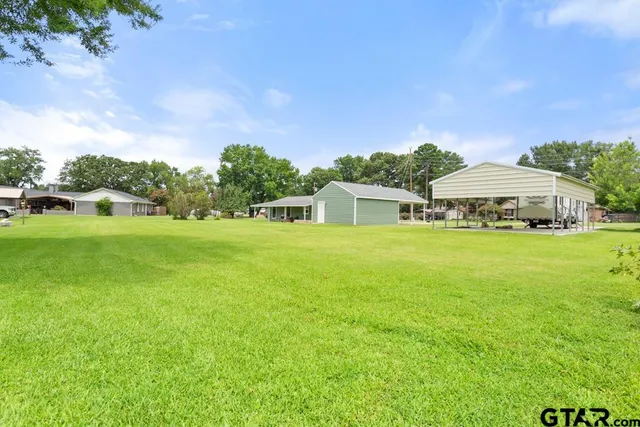 a white house with a big yard and large trees