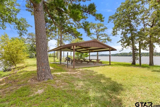 a backyard of a house with table and chairs under an umbrella