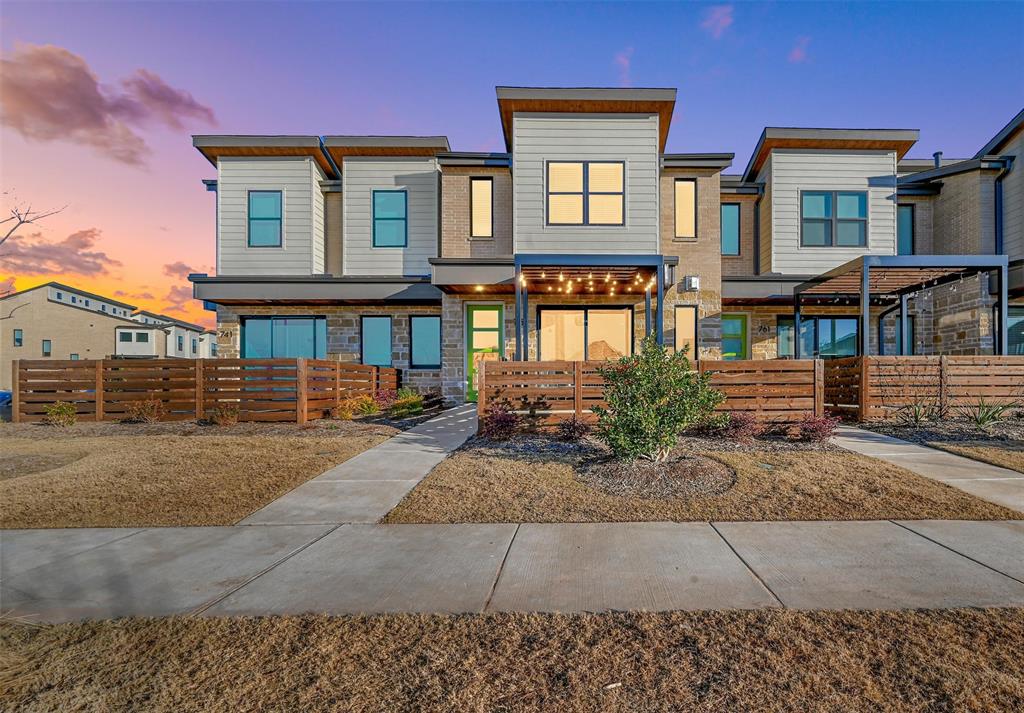 Townhome / multi-family property featuring stone siding and fence