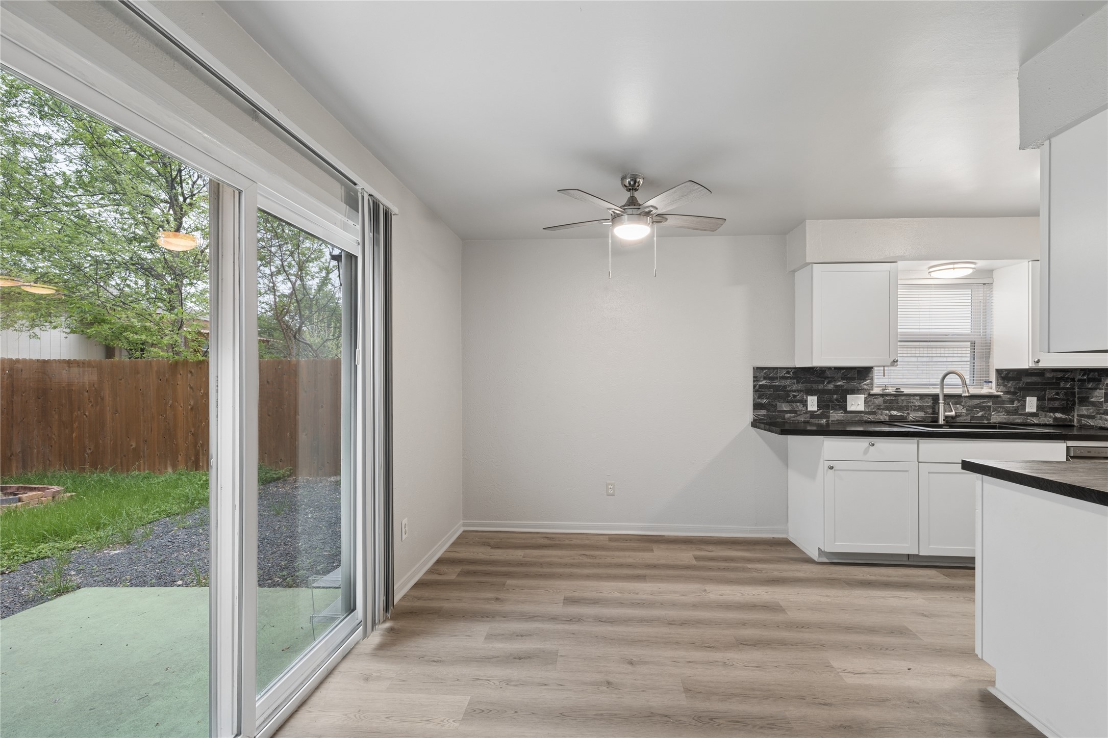 820 Sahara Avenue, Unit B Austin, TX 78745 - Photo 13 of 29 Kitchen with a ceiling fan, dark countertops, white cabinets, light wood-type flooring, and tasteful backsplash