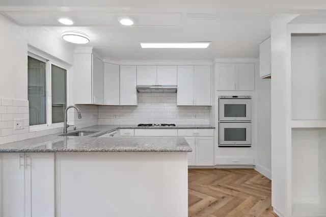 a kitchen with stainless steel appliances granite countertop a stove a sink and a microwave