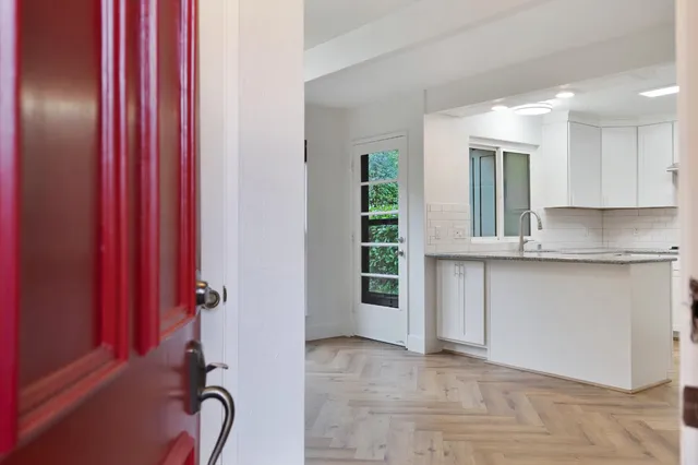 a large white kitchen with kitchen island a sink wooden floor and a counter top space