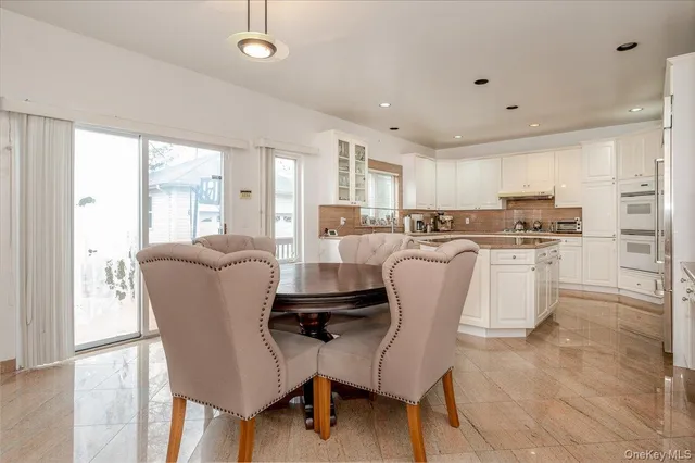 a living room with stainless steel appliances furniture a refrigerator and a kitchen view