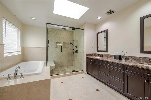 a bathroom with a granite countertop double vanity sink large mirror and shower