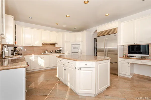 a kitchen with stainless steel appliances granite countertop a stove top oven a sink a refrigerator and white cabinets