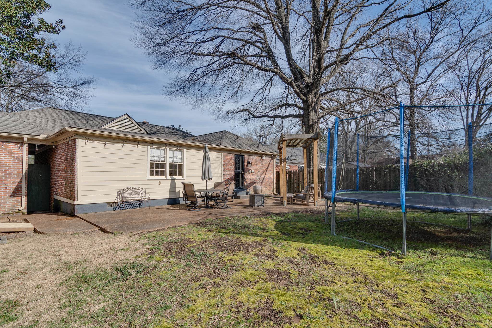 337 North White Station Road Memphis, TN 38117 - Photo 33 of 37 Back of house with a trampoline, brick siding, a yard, a patio area, and fence