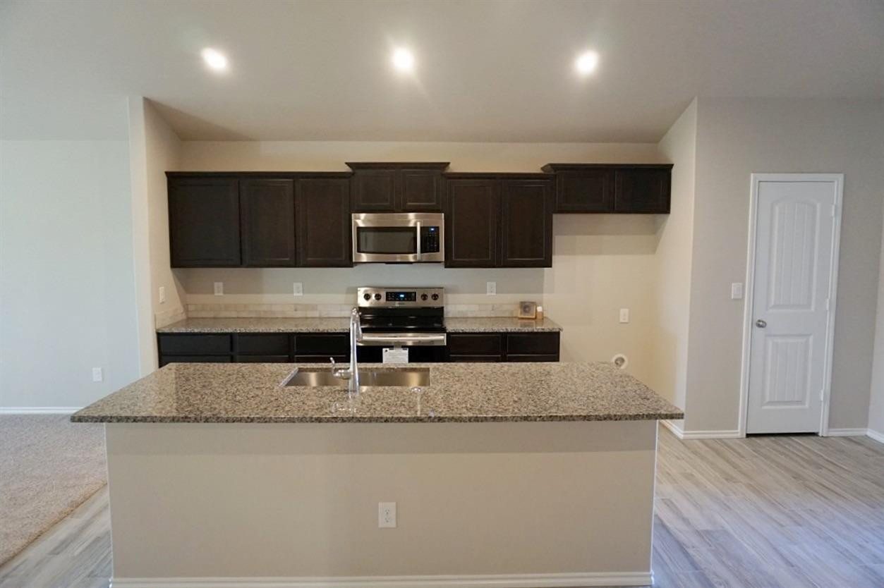 6822 40th Street Lubbock, TX 79407 - Photo 3 of 10 a kitchen with kitchen island granite counter tops and white cabinets