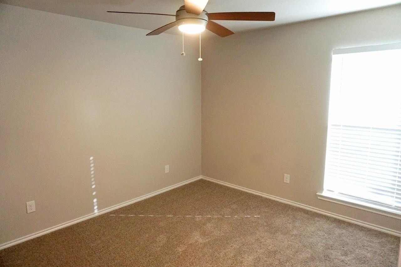 6822 40th Street Lubbock, TX 79407 - Photo 5 of 10 an empty room with a window and a fan