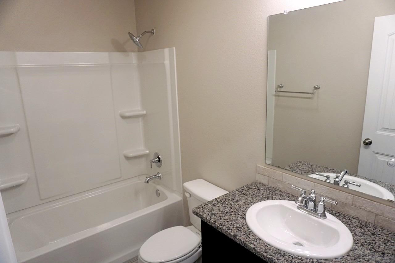 6822 40th Street Lubbock, TX 79407 - Photo 6 of 10 a bathroom with a granite countertop sink toilet and shower