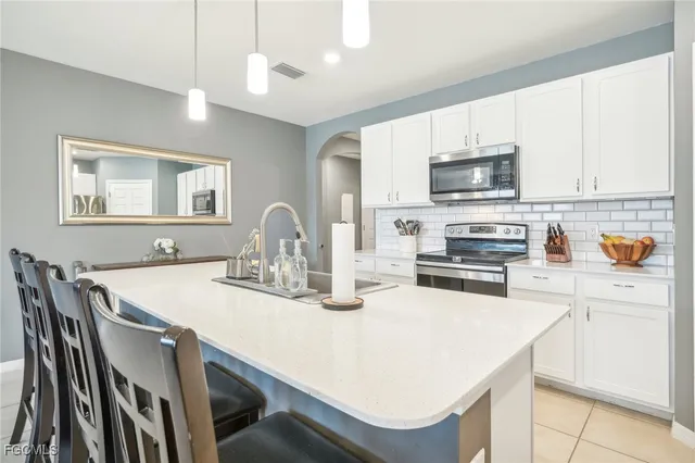 a kitchen with stainless steel appliances a sink table and chairs