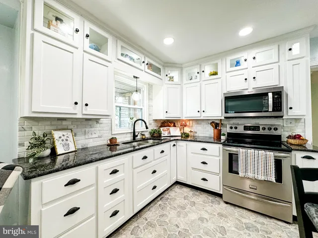 a kitchen with stainless steel appliances white cabinets a sink and a stove