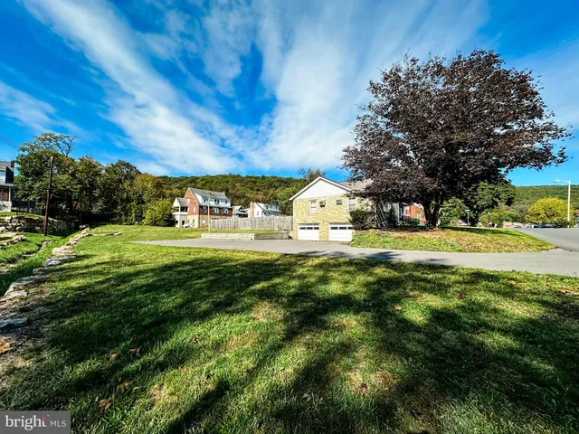a view of a house with a big yard and large trees