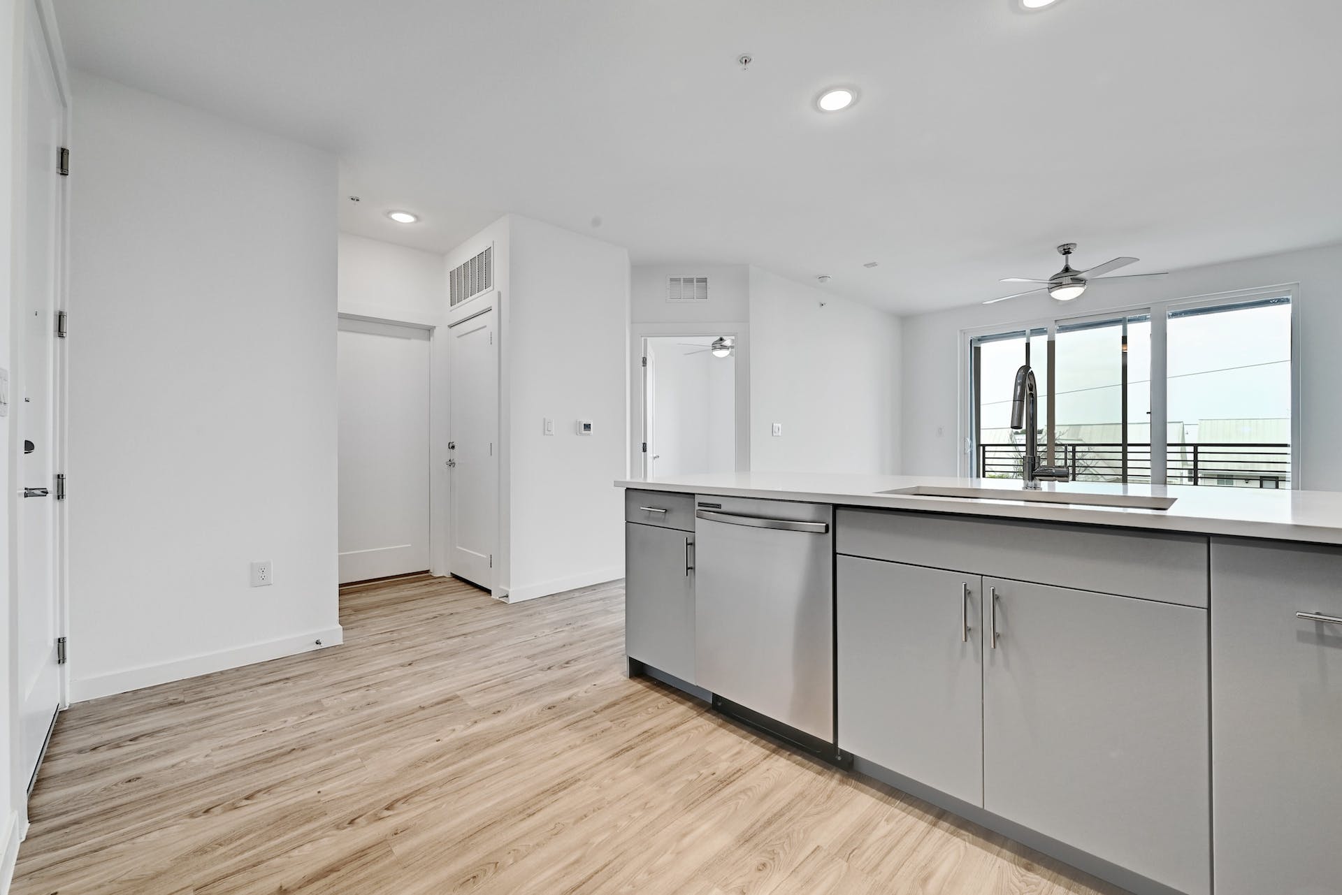 4801 Springdale Road, Unit 1301 Austin, TX 78723 - Photo 4 of 39 A sleek island kitchen featuring modern appliances and light wood flooring, with a balcony view.