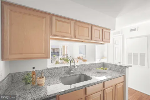 a kitchen with granite countertop a sink and a white cabinets