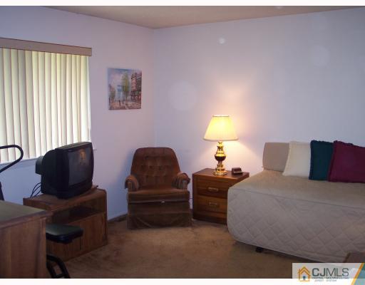 8006 Hana Road Edison, NJ 08817 - Photo 5 of 9 a bedroom with furniture and a lamp