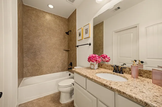 a bathroom with a granite countertop sink mirror vanity bathtub and toilet