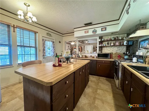 a kitchen with stainless steel appliances granite countertop a sink a stove top oven a counter space and cabinets