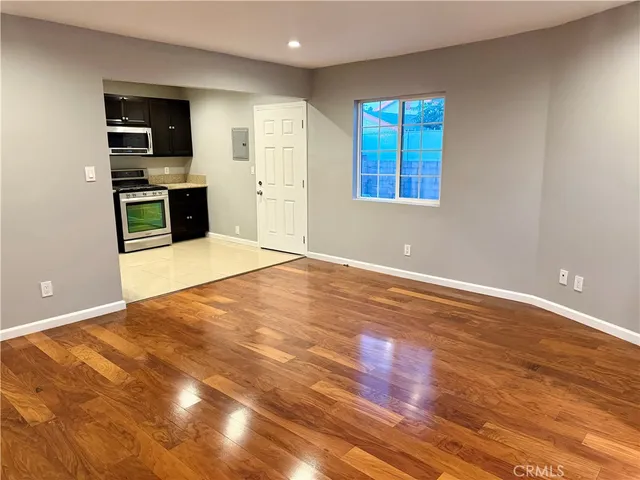 a view of an empty room with wooden floor and windows