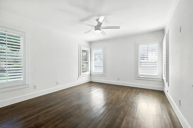an empty room with wooden floor window and ceiling fan