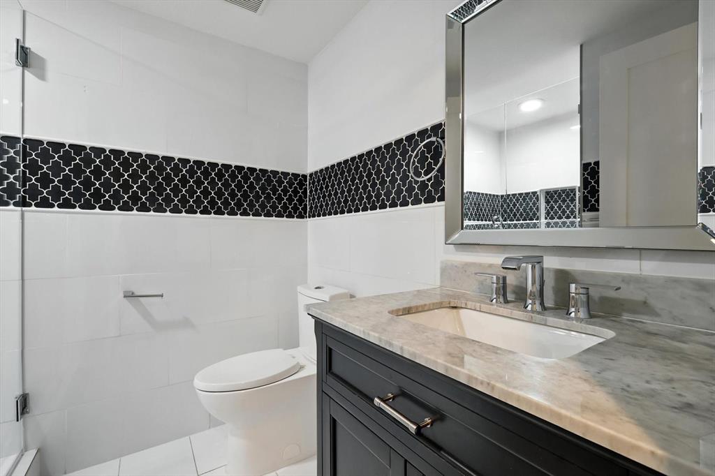 6116 St Moritz Avenue Dallas, TX 75214 - Photo 27 of 40 a bathroom with a granite countertop sink a toilet and a mirror