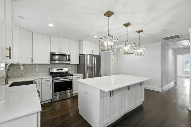 a kitchen with stainless steel appliances a kitchen island hardwood floor sink and stove