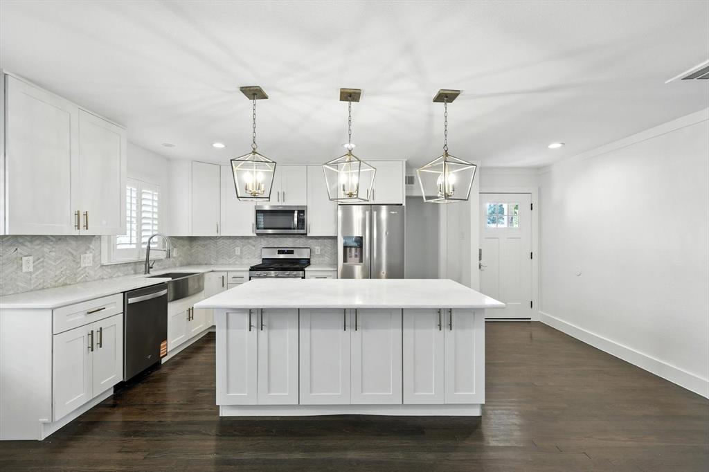 6116 St Moritz Avenue Dallas, TX 75214 - Photo 10 of 40 a kitchen with stainless steel appliances kitchen island granite countertop a table chairs in it and wooden floors