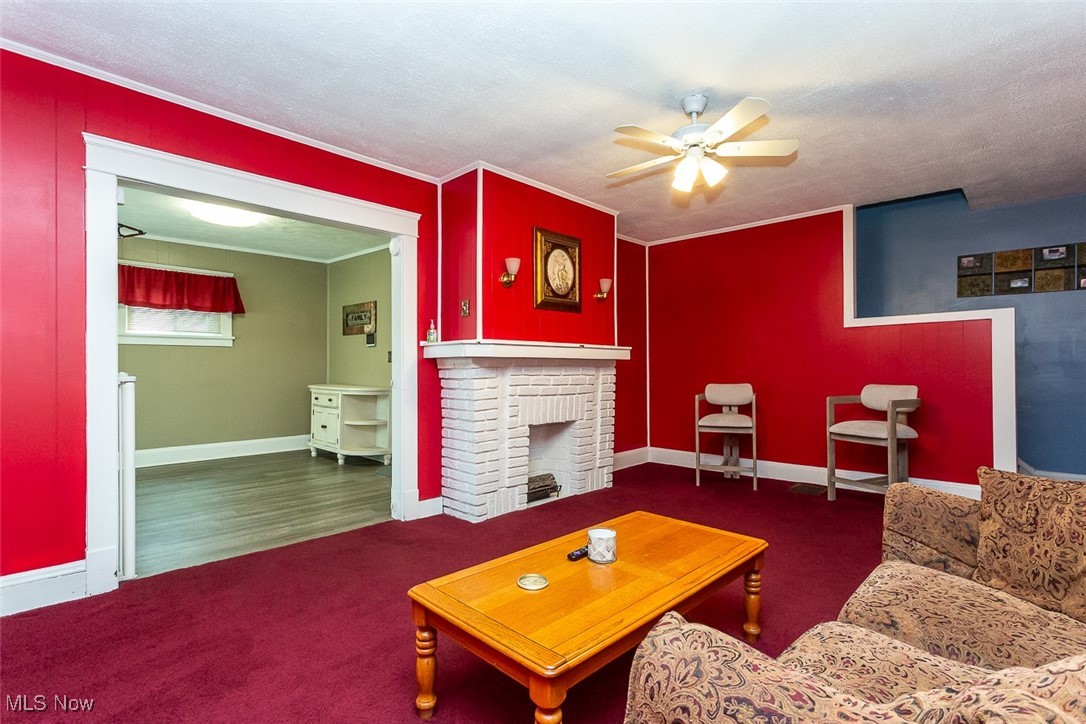 4753 Blythin Road Cleveland, OH 44125 - Photo 6 of 37 Carpeted living room with a ceiling fan, a brick fireplace, and crown molding