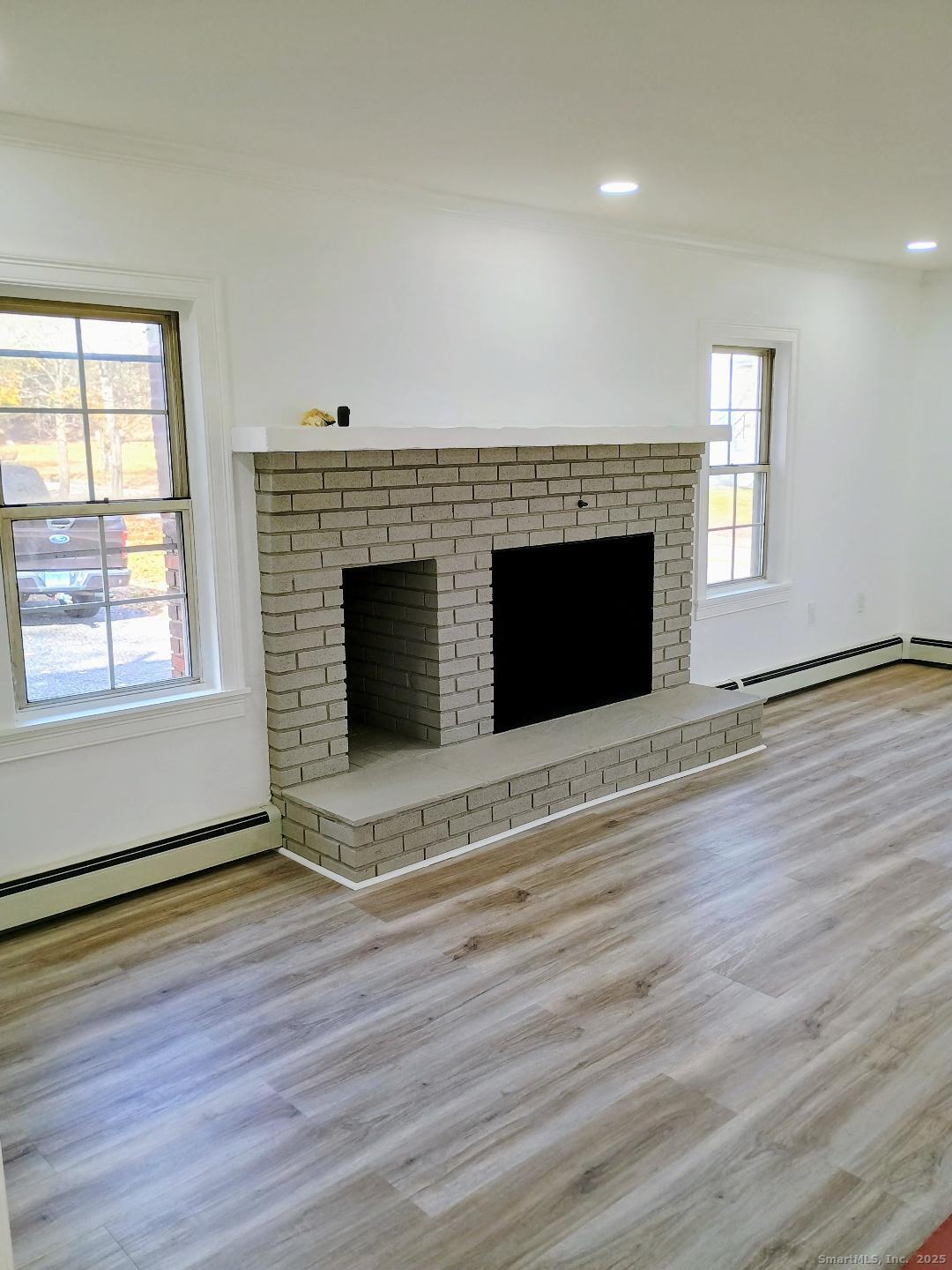 633 Wauregan Road Brooklyn, CT 06234 - Photo 3 of 15 an empty room with wooden floor fireplace and windows