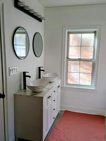 a bathroom with a granite countertop double vanity sink a mirror and a window