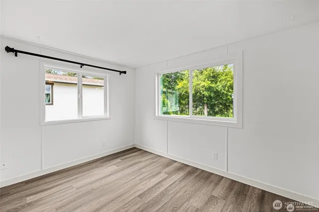 an empty room with wooden floor and windows