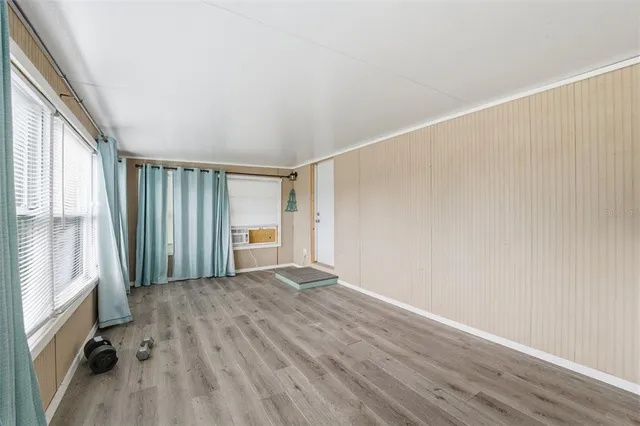 a view of an empty room with a window and wooden floor