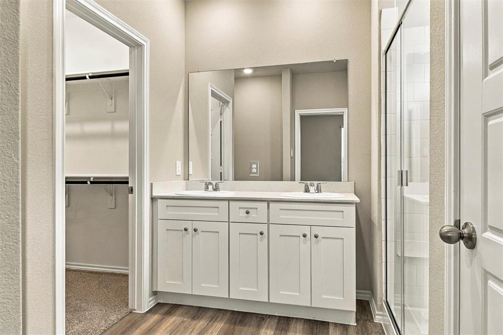 15932 Stableford Road Justin, TX 76247 - Photo 17 of 35 Dual vanity with integrated sinks, wood-finish flooring, frameless glass shower enclosure, and built-in closet shelving