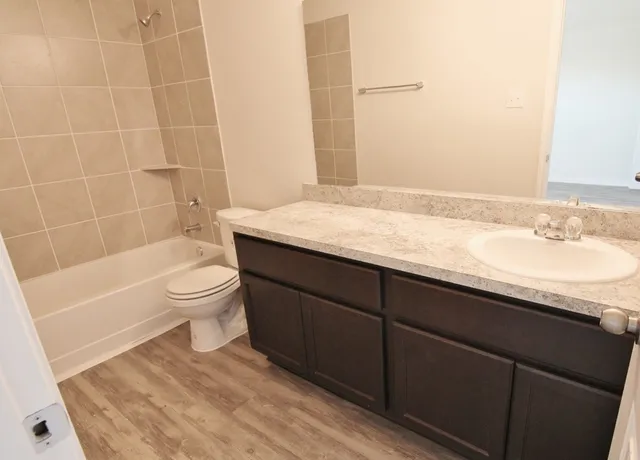 a bathroom with a granite countertop sink toilet a mirror and bathtub