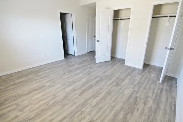 an empty room with wooden floor and a ceiling fan