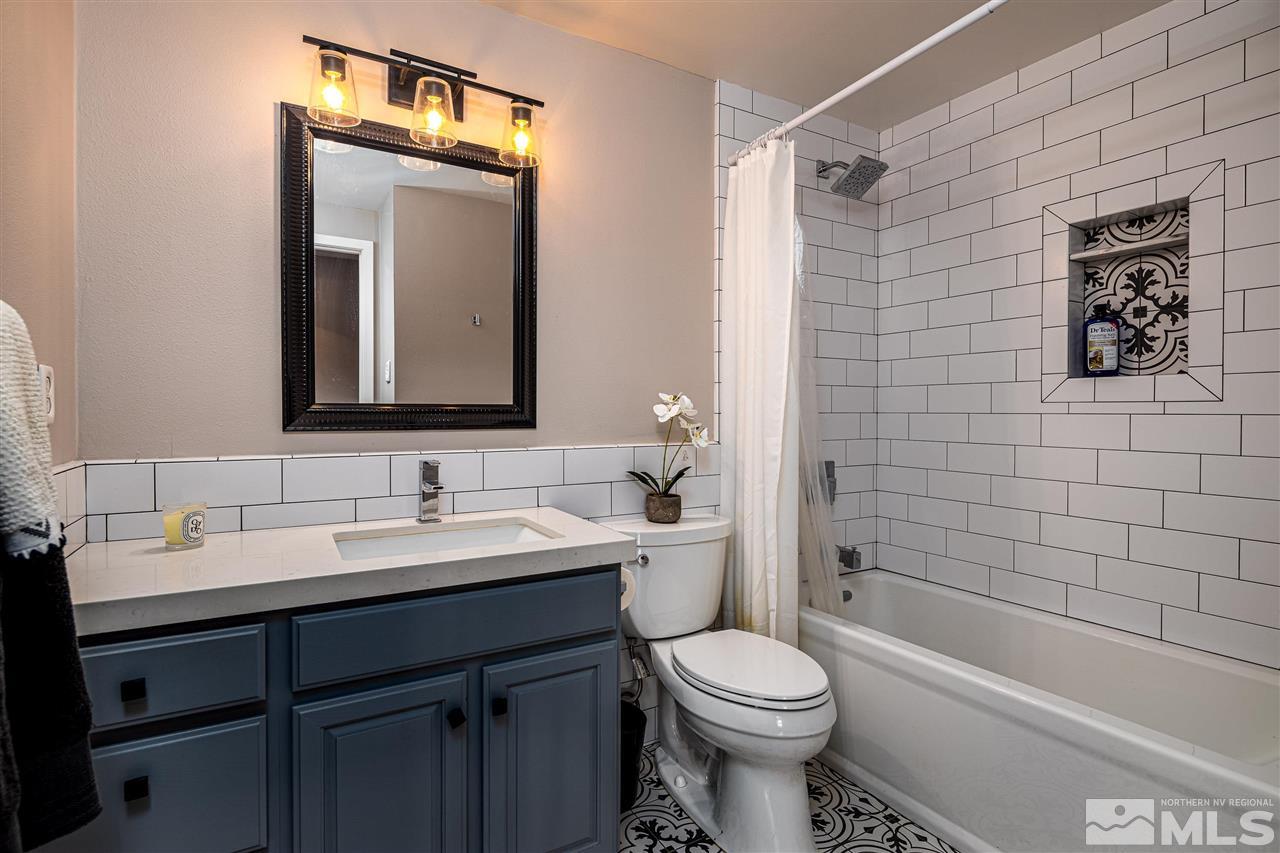 2401 Balsam Street Reno, NV 89509 - Photo 16 of 18 a bathroom with a toilet a sink a mirror a bathtub and shower