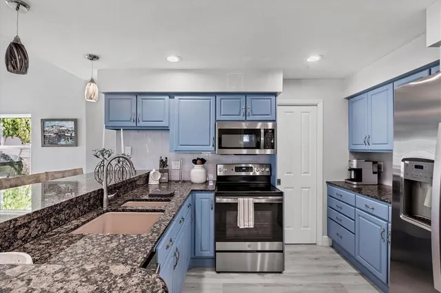 a kitchen with stainless steel appliances granite countertop a stove a sink and a refrigerator