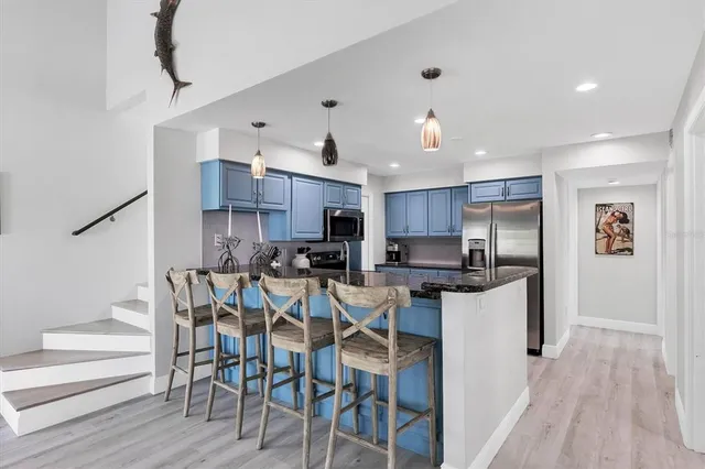 a kitchen with stainless steel appliances kitchen island granite countertop a table chairs and a refrigerator