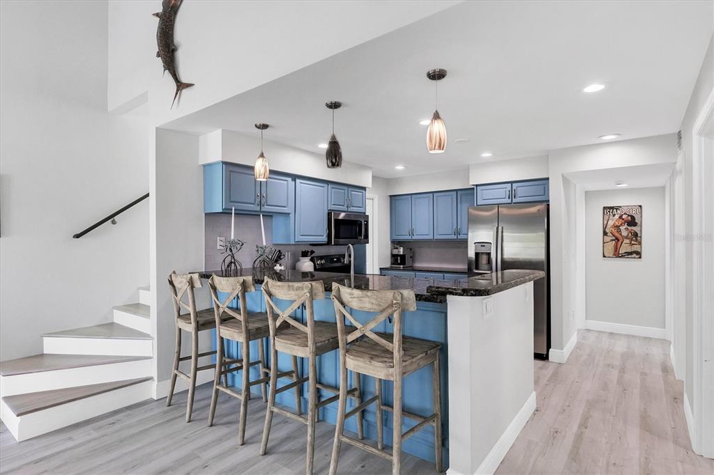 401 Lafitte Street Boca Grande, FL 33921 - Photo 10 of 37 a kitchen with stainless steel appliances kitchen island granite countertop a table chairs and a refrigerator