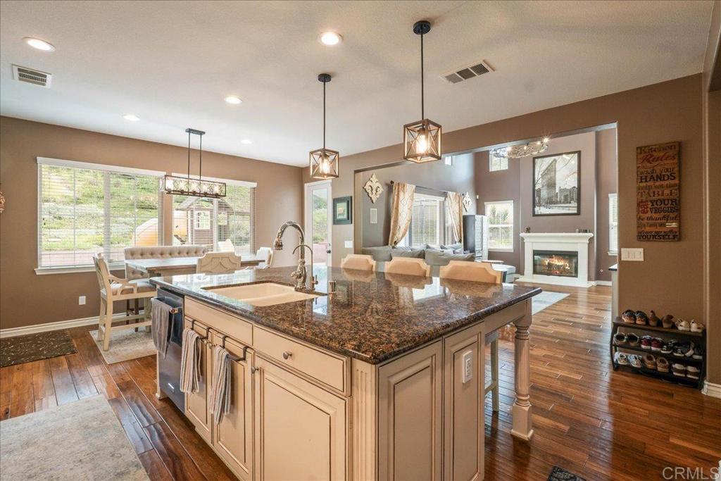 6996 Goldstone Road Carlsbad, CA 92009 - Photo 14 of 49 a kitchen with stainless steel appliances granite countertop a stove a sink dishwasher and a dining table with chairs