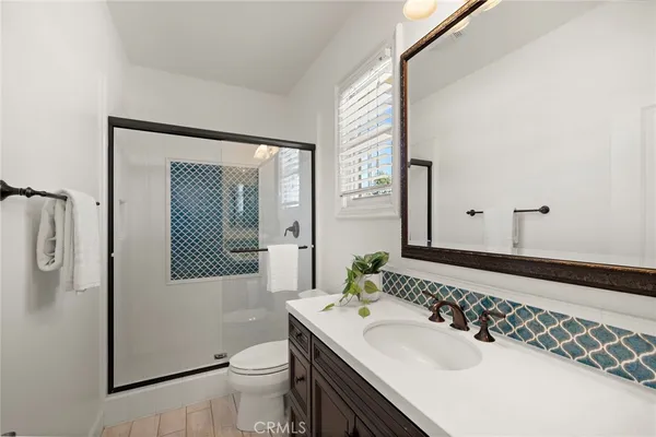 a large living room with a couch a large mirror and a glass door shower