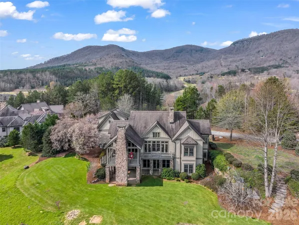 a view of a big house with a big yard and large trees