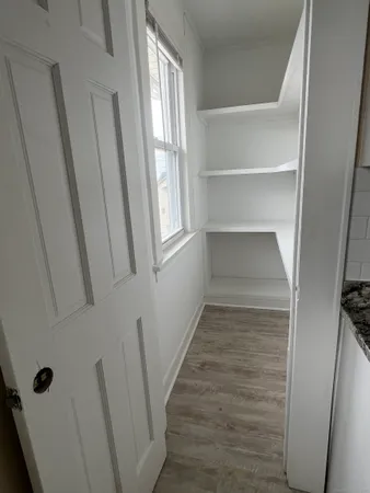 a view of an empty room with wooden floor and stairs