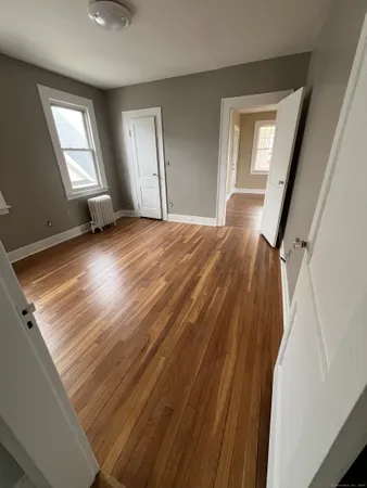 a view of empty room with wooden floor and fan